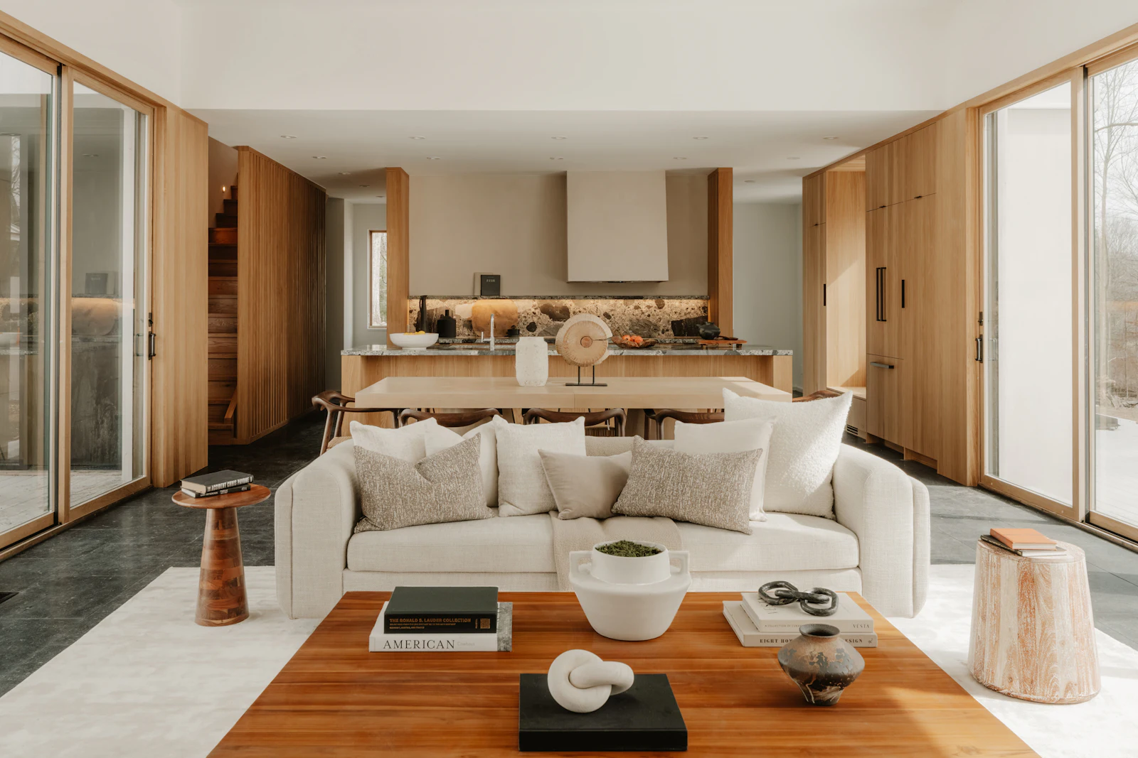 Séjour et cuisine ouverte aux boiseries claires, canapé blanc et table basse en bois