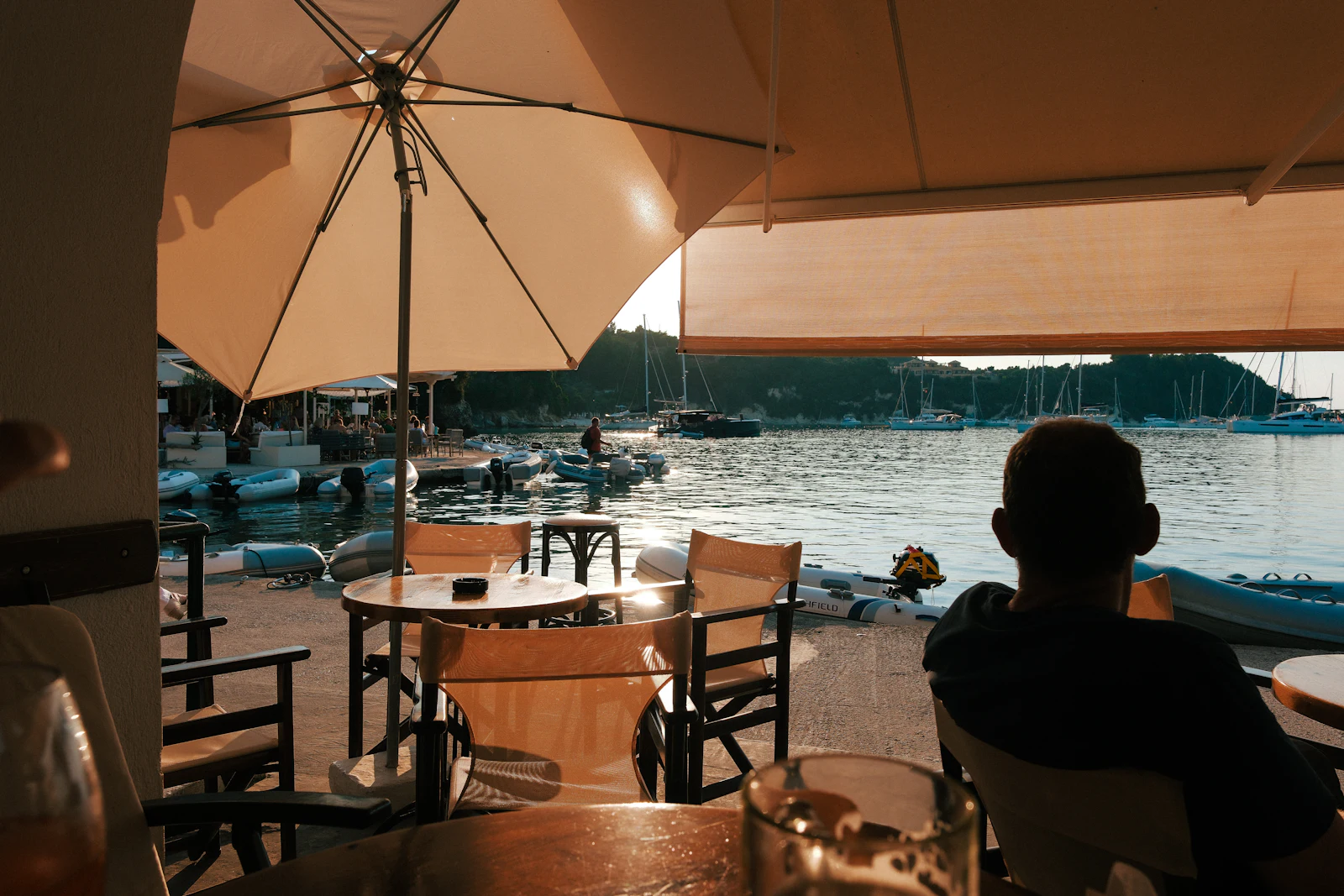Terrasse de restaurant au bord d'un port, au coucher du soleil